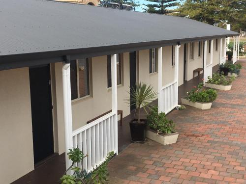 a row of houses with potted plants on a brick sidewalk at Esperance Central Apartments in Esperance