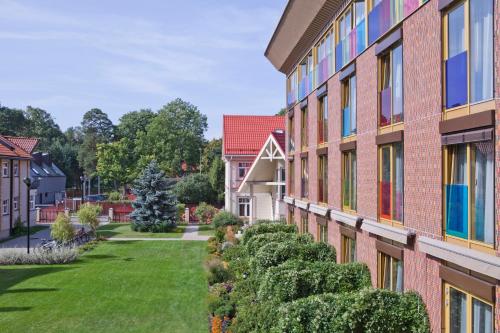 a building with bushes in front of a yard at Kurshi Hotel & Spa in Jūrmala
