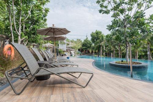 een groep stoelen met een parasol naast een zwembad bij Unixx Pattaya by Alvin in Pattaya South