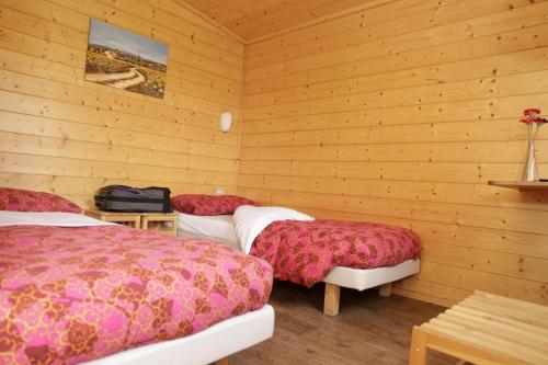 - 2 lits dans une chambre dotée de murs en bois dans l'établissement Agri Village, à Chartreuse de Pavie