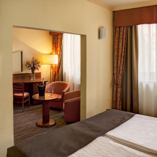 a hotel room with a bed and a table and chairs at Luxury Family Hotel Bílá Labuť in Prague