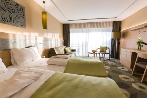a hotel room with two beds and a desk at AIGO Welcome Family Resort in Aigen im Mühlkreis
