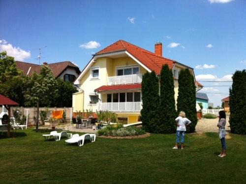 two people standing in the grass in front of a house at Györgyi Haus in Bük