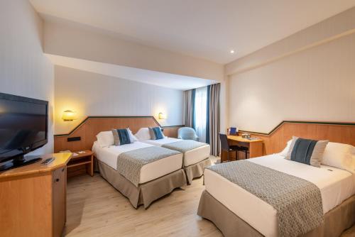 um quarto de hotel com duas camas e uma televisão de ecrã plano em Hotel Praga em Madrid