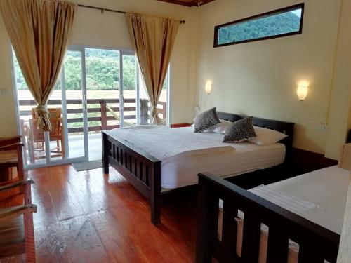 a bedroom with two beds and a balcony at Riverview Bungalows & GH in Muang Ngoy