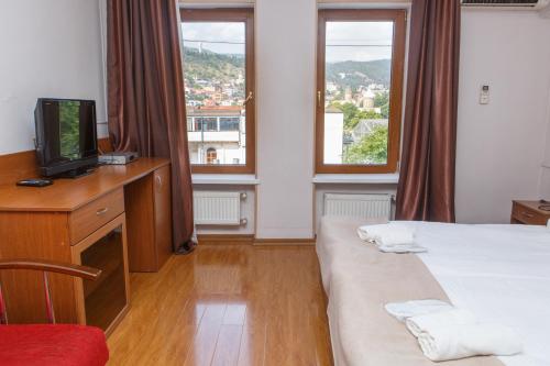 a room with two beds and a desk with a television at Hotel Nata in Tbilisi City