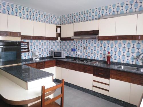 una cocina con armarios blancos y azulejos azules y blancos en Apartamento Ciudad de la Cultura, en Santiago de Compostela