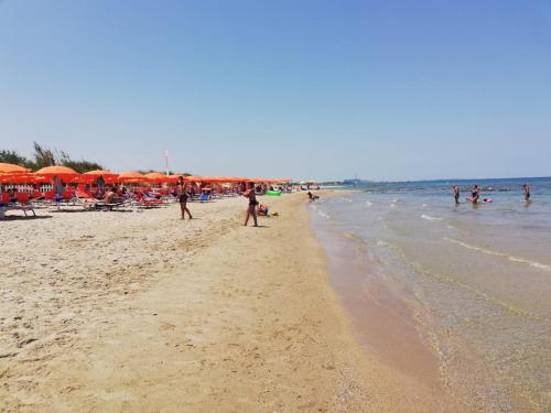 um grupo de pessoas em uma praia com guarda-sóis em Greta Viola House em Squinzano