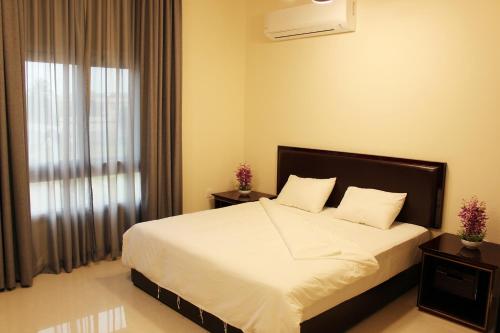 um quarto com uma cama com lençóis brancos e uma janela em Al Noor Plaza em Salalah