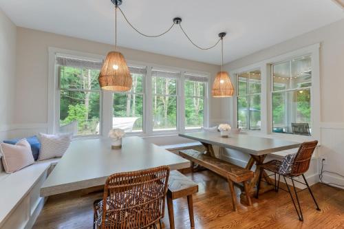 a dining room with a table and chairs and windows at Lake Trail Treehouse in Saugatuck