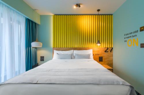 a bedroom with a large bed and a large window at ibis Styles Bucharest Erbas in Bucharest