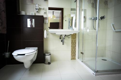 a bathroom with a toilet and a sink and a shower at Hotel Pod Filarami in Czeladź