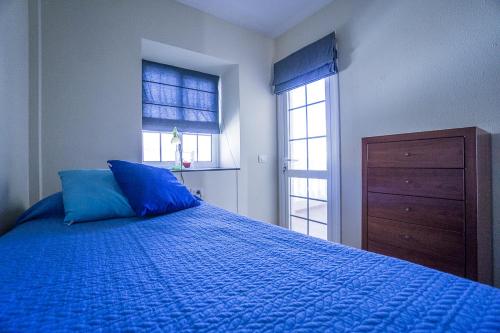 a bedroom with a blue bed and a dresser at Rooms in El Medano in El Médano