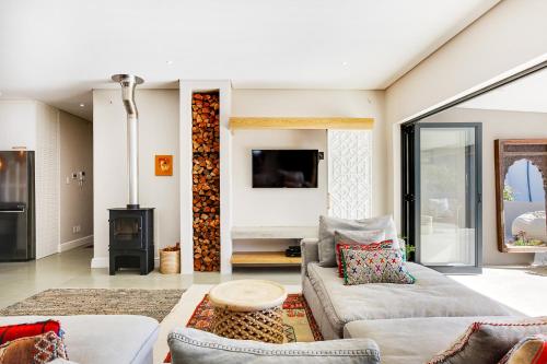 a living room with two couches and a fireplace at Solar-Powered Mountain Retreat with Natural Pool in Cape Town