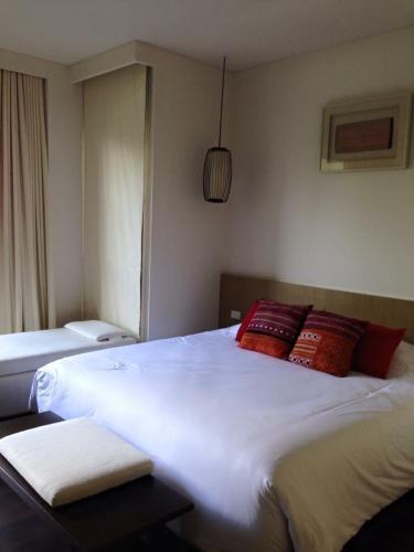 a bedroom with a large white bed with red pillows at My sweet home@ChiangMai in Ban Dong