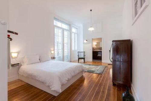 a bedroom with a large white bed and a chair at Wonderful balcony over Clérigos Tower in Porto