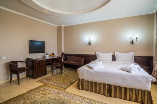 una camera d'albergo con letto, scrivania e TV di Royal Petrol Hotel a Almaty