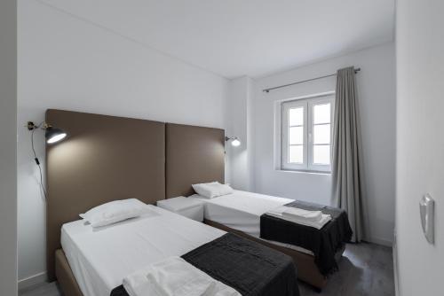 リスボンにあるCity Stays Atalaia Apartmentsのベッド2台と窓が備わるホテルルームです。