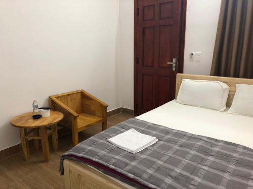 a bedroom with a bed and a table and a chair at An Ngọc Linh Hotel in Bao Loc