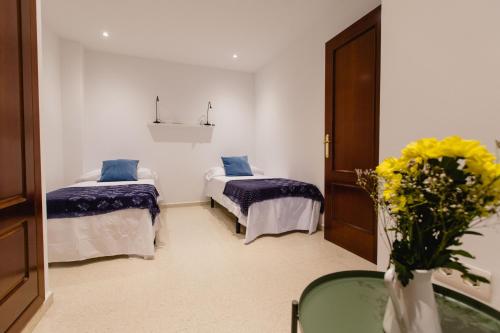 Zimmer mit 2 Betten und einer Blumenvase in der Unterkunft Apartamento El Patio de Canovas in Cádiz