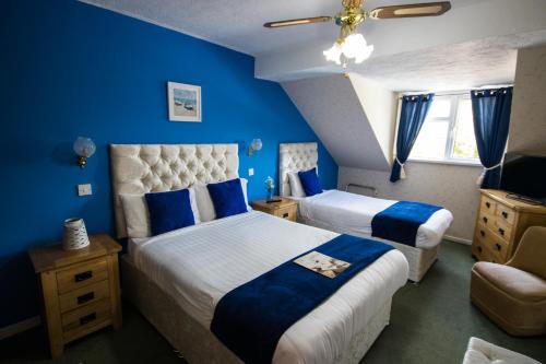 1 dormitorio con 2 camas, paredes azules y techo en The White Hart Inn, en Llandeilo