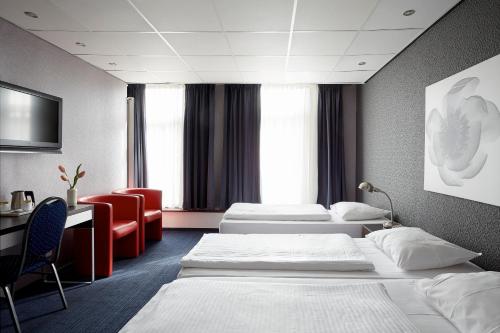 una camera d'albergo con tre letti e una scrivania di Hotel D'Amsterdam Leidsesquare ad Amsterdam