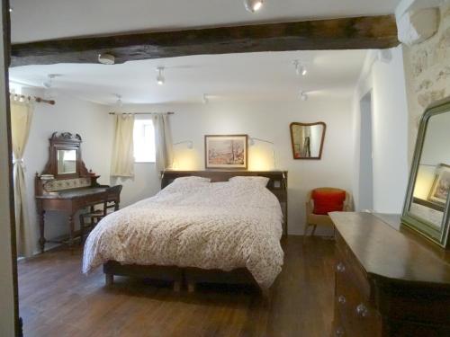 a bedroom with a bed and a desk and a mirror at La Maison de Pierre in Flavigny-sur-Ozerain