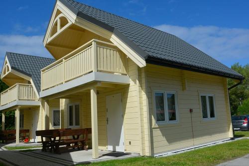 uma pequena casa amarela com um deque e uma mesa em Domki letniskowe Azalia em Ustronie Morskie
