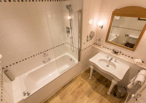 a bathroom with a tub and a sink and a shower at Kilworth House Hotel and Theatre in Lutterworth
