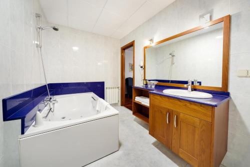 a bathroom with a tub and a sink and a mirror at Hotel As Camelias in Vilarrodis