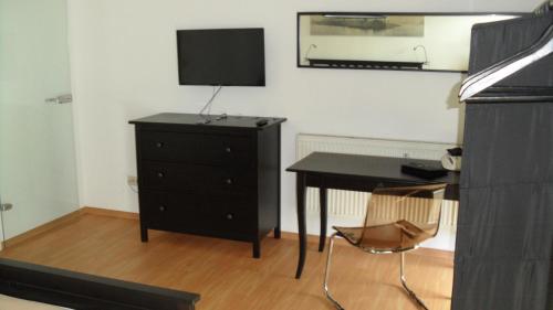 una camera da letto con scrivania e comò con televisore di Central City Apartment Würzburg a Würzburg