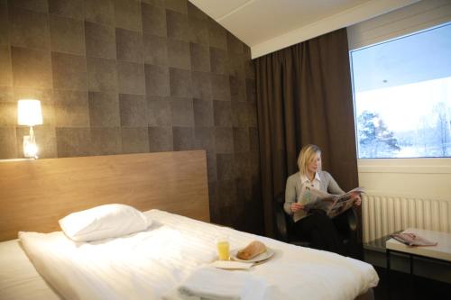 a woman sitting next to a bed in a hotel room at Laponia Hotell & Konferens in Arvidsjaur