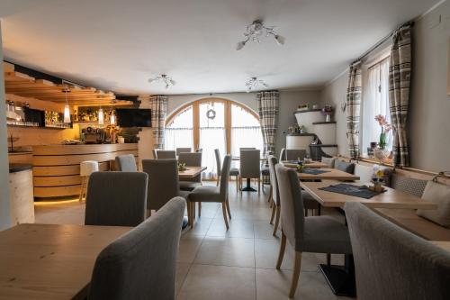 um restaurante com mesas e cadeiras e uma cozinha em Aparthotel Dolomites Living&Relax em Commezzadura