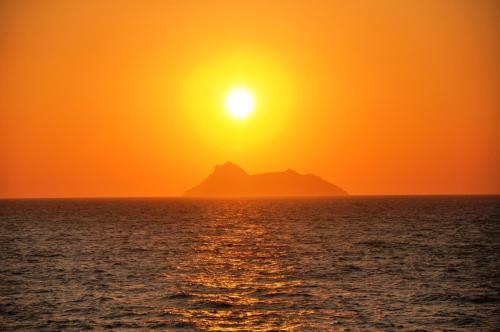 a sunset over the ocean with a mountain in the background at Hotel Sofia in Matala