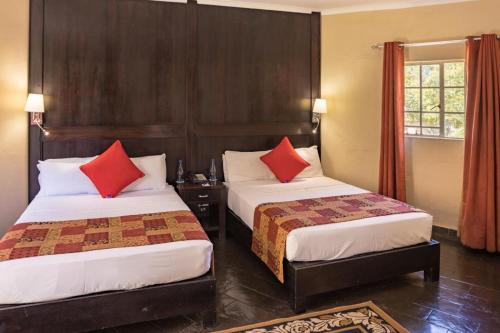 um quarto de hotel com duas camas com almofadas vermelhas em Shumba Valley Lodge em Lanseria