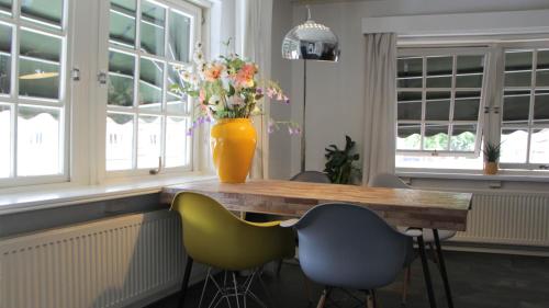 een vaas met bloemen op een houten tafel met stoelen bij La vita e bella in Ootmarsum