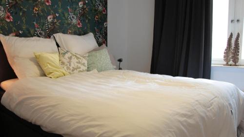 Una cama con sábanas blancas y almohadas en un dormitorio en La vita e bella, en Ootmarsum