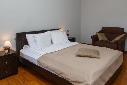 a bedroom with a large bed and a chair at Hotel Nata in Tbilisi City