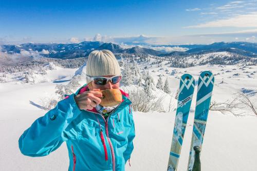 a man eating a sandwich on top of a snow covered mountain at Goldenfields apartment in Kranj