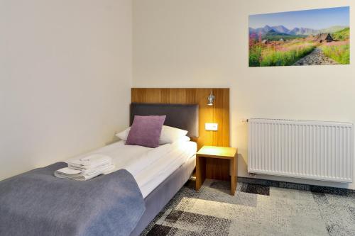 a bedroom with a large bed with a purple pillow at Hotel Bystra in Białka Tatrzanska