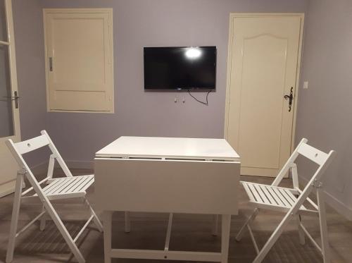 una camera con due sedie, un tavolo e una TV di Les volets rouges a Châteauneuf-du-Pape