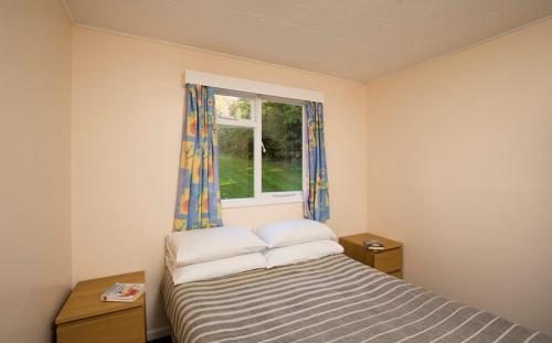 a small bedroom with a bed and a window at Whitecliff Bay Holiday Park in Bembridge