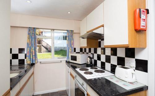 a kitchen with a black and white checkered wall at Whitecliff Bay Holiday Park in Bembridge