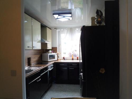 a kitchen with a black refrigerator and a window at Private Apartment Laatzen City in Hannover