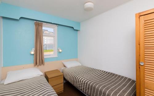 two beds in a room with blue walls and a window at Whitecliff Bay Holiday Park in Bembridge
