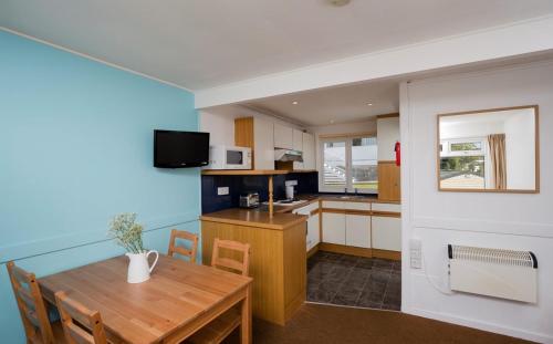 a kitchen and dining room with a wooden table at Whitecliff Bay Holiday Park in Bembridge