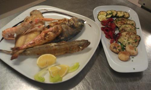 a plate of food with seafood and vegetables on a table at Hotel Giannino in Porto Recanati