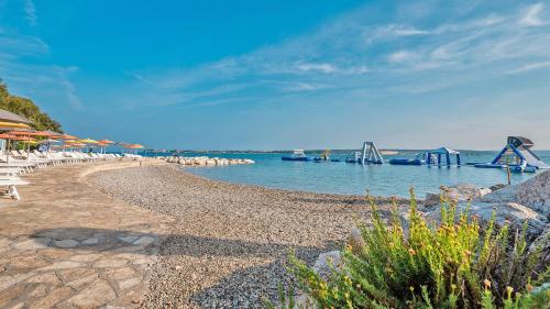a beach with chairs and a bridge in the water at Valamar Tamaris Resort in Tar