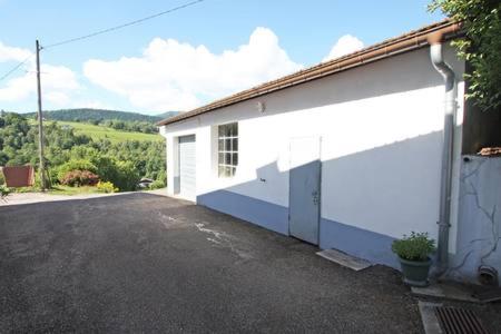 a white building with a garage and a driveway at Gîte de famille dans les Vosges in Saint-Maurice-sur-Moselle