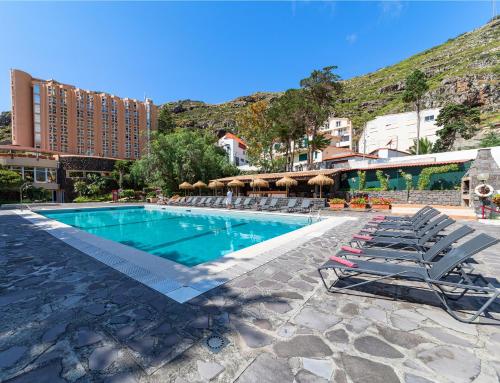 a swimming pool with lounge chairs and a hotel at Dom Pedro Madeira in Machico